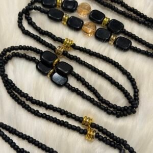 Dinner for Two waist beads with matte black beads, gold accents, and amber details on a soft background